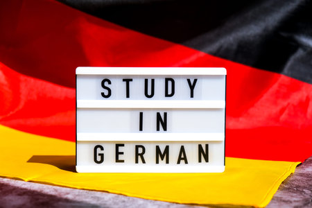 Lightbox with text STUDY IN GERMAN National symbol of Germany. German wave silky flag background. Education and learningの写真素材