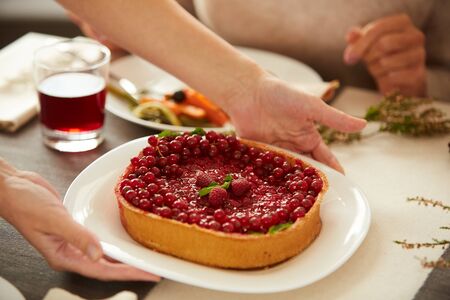 Close-up of woman putting berry sweet pie on the table during holiday dinnerの写真素材