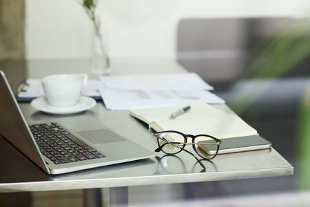 Close-up of table with laptop computer eyeglasses and documents at officeの写真素材