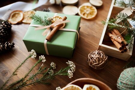 Image of gift box in green wrapping paper decorated with fir branch and cinnamon on for Christmas holidayの写真素材