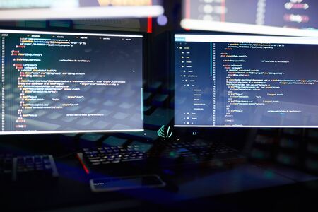 Image of two computer monitors installing the new software in dark officeの写真素材