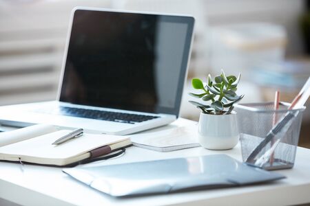 Close-up of laptop with blank screen with note pad and documents on the table at modern officeの写真素材