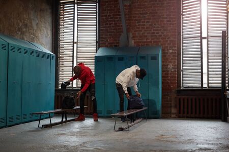 Two African sportsmen unpacking their bags in locker room they going in sports trainingの写真素材