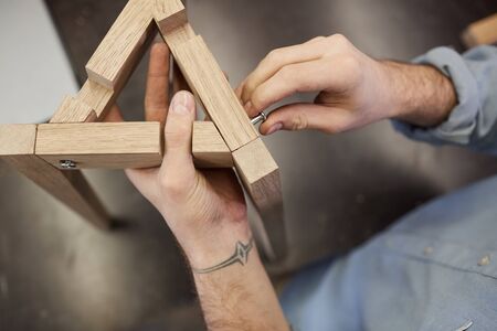 Close-up of man making figure or furniture from wood he standing and tightening the screwの写真素材