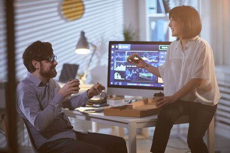 Businessman and businesswoman have a break at office they eating pizza and drinknig coffee and...