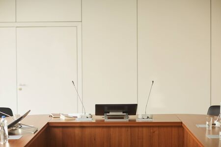 Image of big wooden table with monitor and microphones on it at modern board room