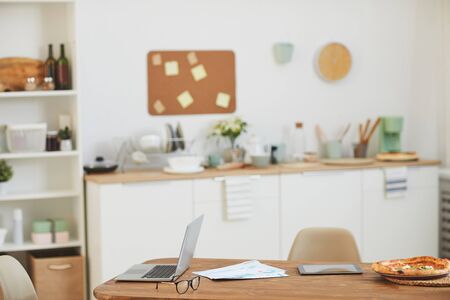 Image of wooden table with laptop and pizza on it in the empty kitchen at homeの写真素材