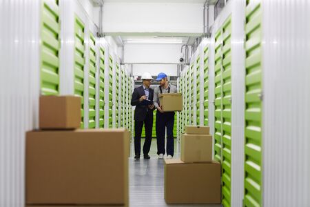 Image of storage room with boxes and two men walking and talking in the backgroundの写真素材