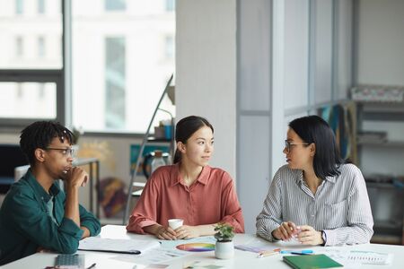 Multiethnic group of young business people thinking over new plan together during business meeting at officeの写真素材