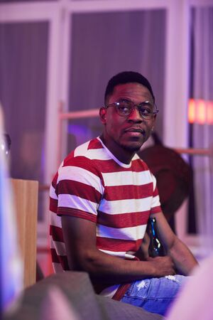 Portrait of African young man sitting on sofa at the party