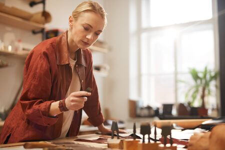 Horizontal shot of young adult beautiful woman wearing casual outfit choosing stitching chisel for...