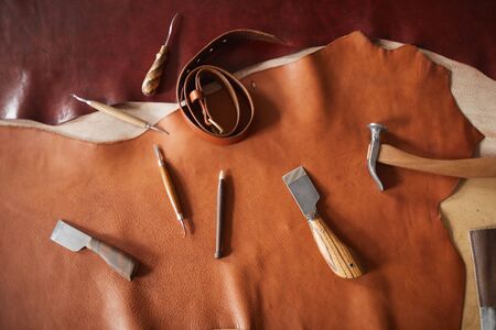 Horizontal from above flat lay shot of various tools for craftwork with leather materials lying on...
