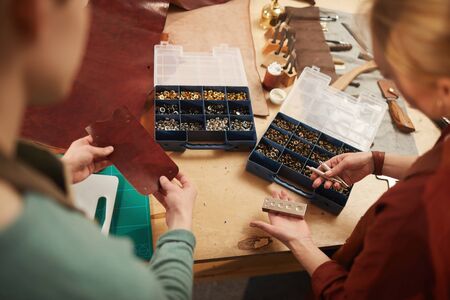 Horizontal high angle shot of unrecognizable artisans choosing snap fasteners suitable for new...