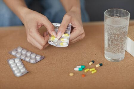 Close-up of woman drinking pills from disease at the table at home