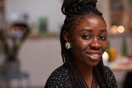 Portrait of young beautiful African woman with elegant hairstyle smiling at camera