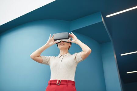 Young beautiful woman wearing virtual glasses watching some virtual reality outdoors