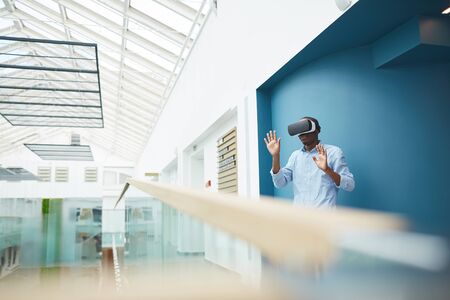African businessman wearing virtual glasses standing and gesturing he talking to his colleague...