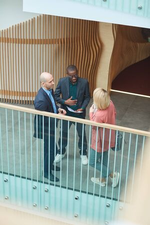 Group of business people standing and talking to each other they discussing documents at office...