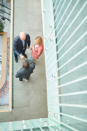 High angle view of business people shaking hands they greeting each other before meeting at office corridorの写真素材