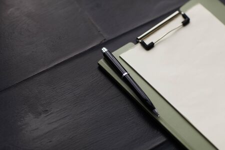 Close-up of blank paper on the clipboard with pen on the wooden table