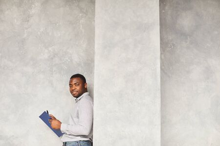 Portrait of African young businessman holding document and looking at camera against the white...