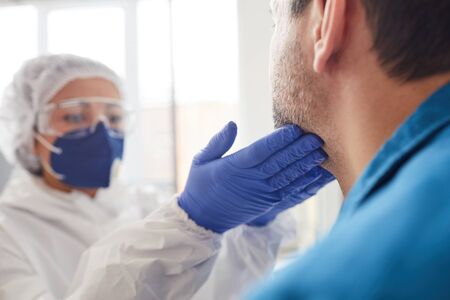 Close-up of nurse in protective clothing examining the patients throat during medical exam at hospitalの写真素材