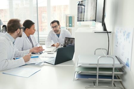 Team of doctors sitting at the table and discussing problems together during a business meeting at officeの写真素材