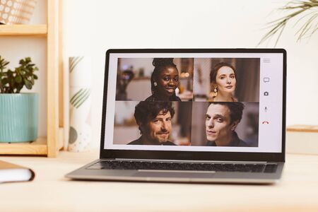 Group of young friends looking at camera from the monitor of laptop they have online conference