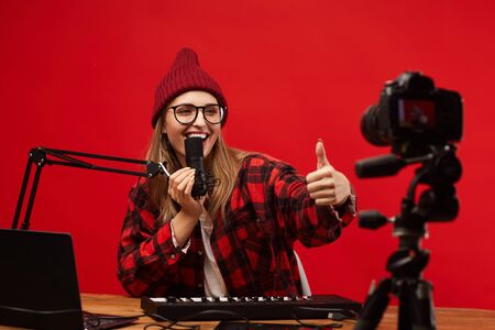 Young smiling woman in eyeglasses showing thumb up to the camera and singing she shooting the contentの写真素材
