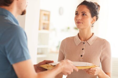 Young woman getting parcels from delivery man she has delivery to homeの写真素材
