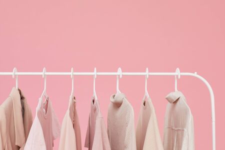Close-up of dresses and shirts hanging on the rack isolated on pink backgroundの写真素材