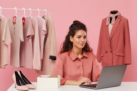 Young woman sitting at the table and using laptop she buying clothes onlineの写真素材