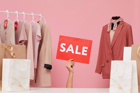 Image of female hand holding Sale placard in the clothes shopの写真素材