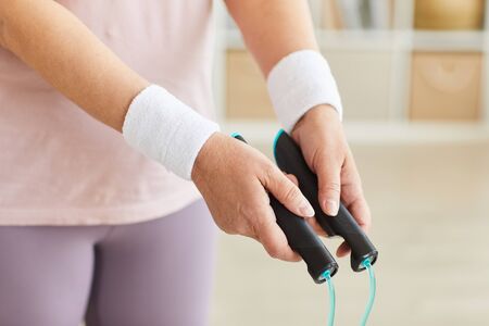 Close-up of senior woman holding skipping rope in her hands and doing sports exercises