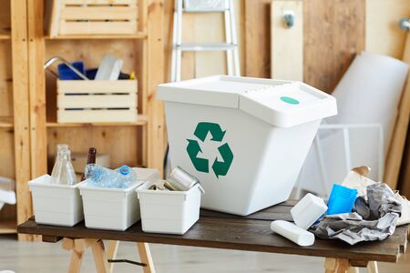 Image of big plastic container for garbage and sorted waste in small boxes on the tableの写真素材