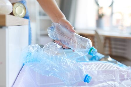Close-up of female hand sorting plastic bottles she throwing bottles into the other bin
