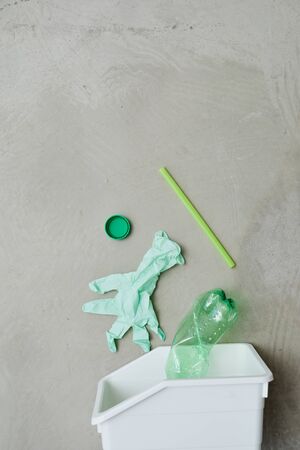 Close-up of plastic trash bin with different garbage in it isolated on grey backgroundの写真素材