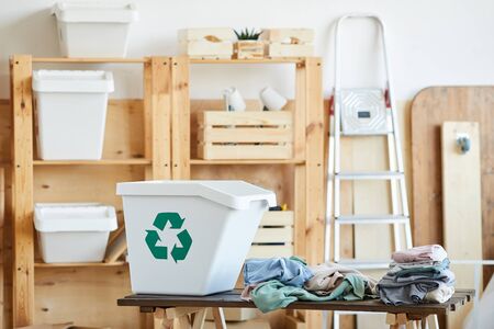 Image of big plastic bin and old clothes on the table in storage roomの写真素材