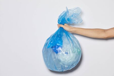 Close-up of female hand holding package with garbage against the white background
