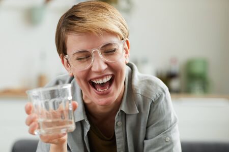 Young woman with short hair drinking alcohol and laughing she having fun at the party