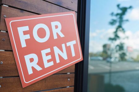 Close-up of placard For Rent hanging on the door of modern office building