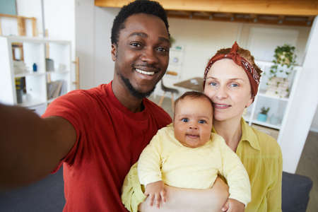 Portrait of happy family with baby girl smiling at camera they making selfie portrait