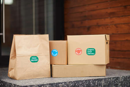 Close-up of cardboard boxes and packages on the ground before the door outdoors