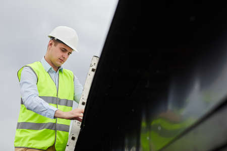 Man in work helmet and in vest working outdoors in the construction siteの写真素材