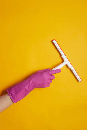 Close-up of woman in rubber gloves using sponge to clean the surface isolated on yellow backgroundの写真素材