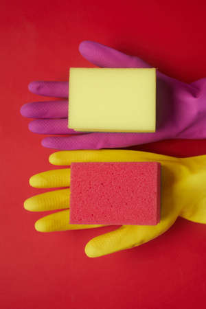 High angle view of colorful rubber gloves and sponges for cleaning isolated on red backgroundの写真素材