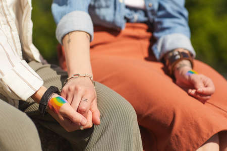 Close-up of two young girlfriends holding hands while sitting outdoors