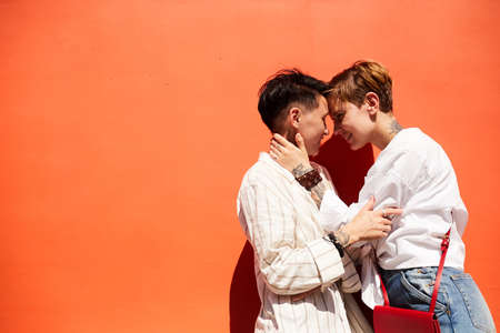 Two young lesbians embracing and enjoying each other against the red background