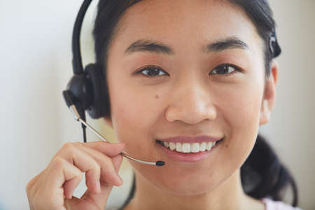 Close-up of Asian young operator in headphones smiling at cameraの写真素材