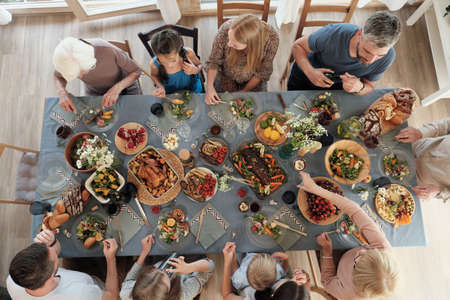 High angle view of big family sitting at the table and having dinner together at homeの写真素材